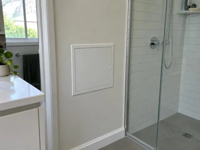 Neat access panel in a bathroom wall beside a tiled shower and vanity in Beverly Hills